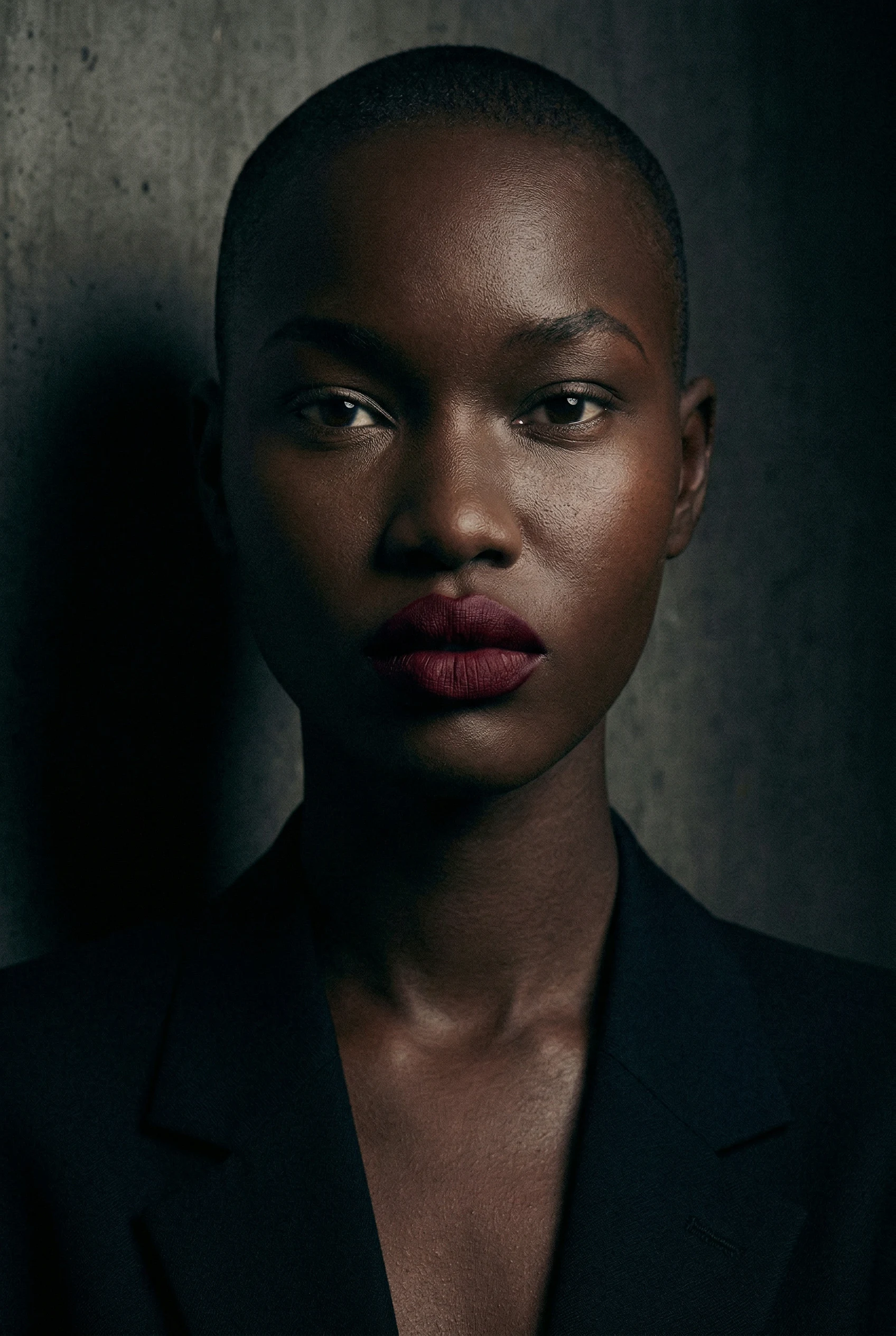 Beauty portrait in a dark blazer against raw concrete