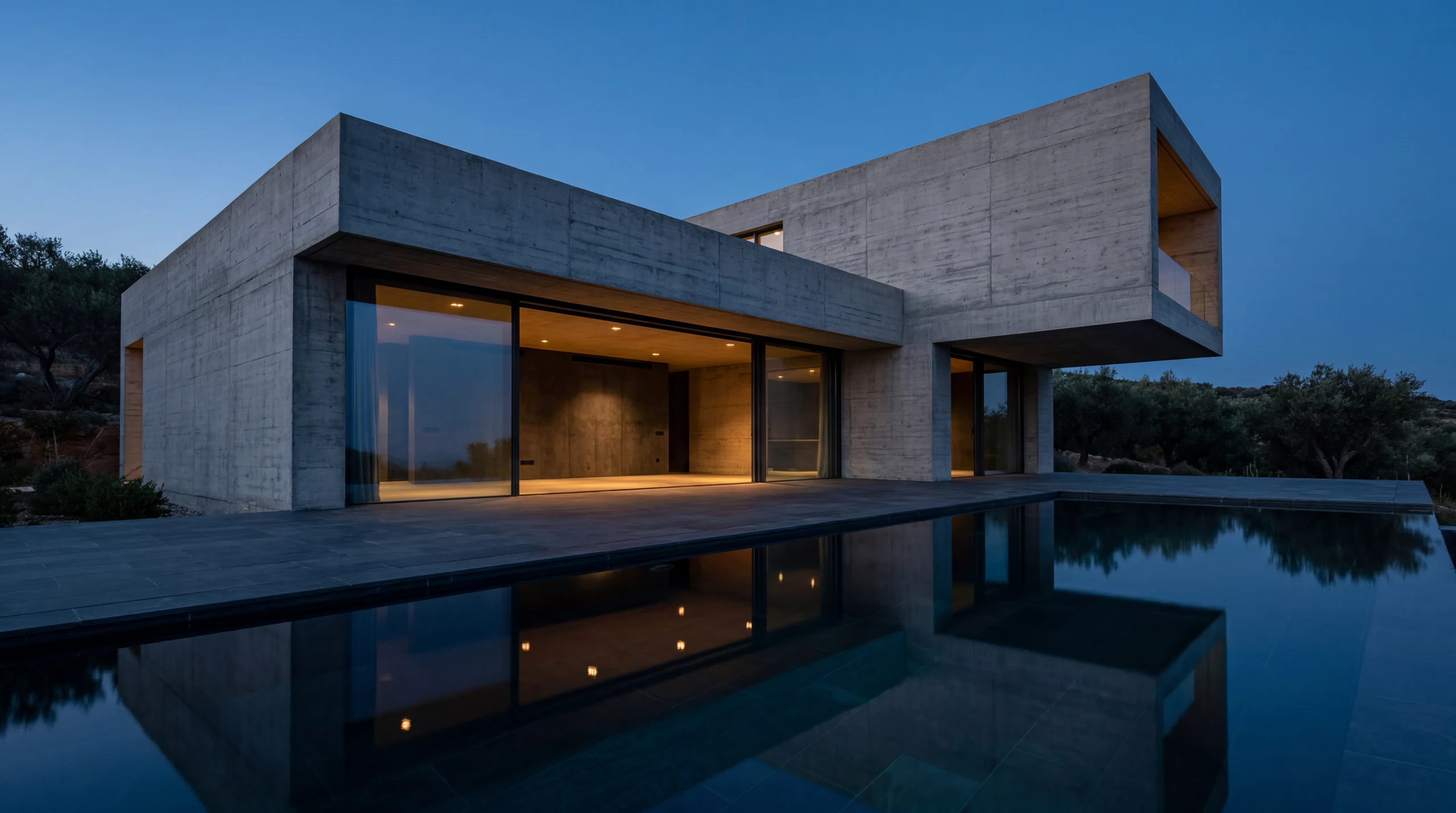 Concrete villa with a reflecting pool at dusk