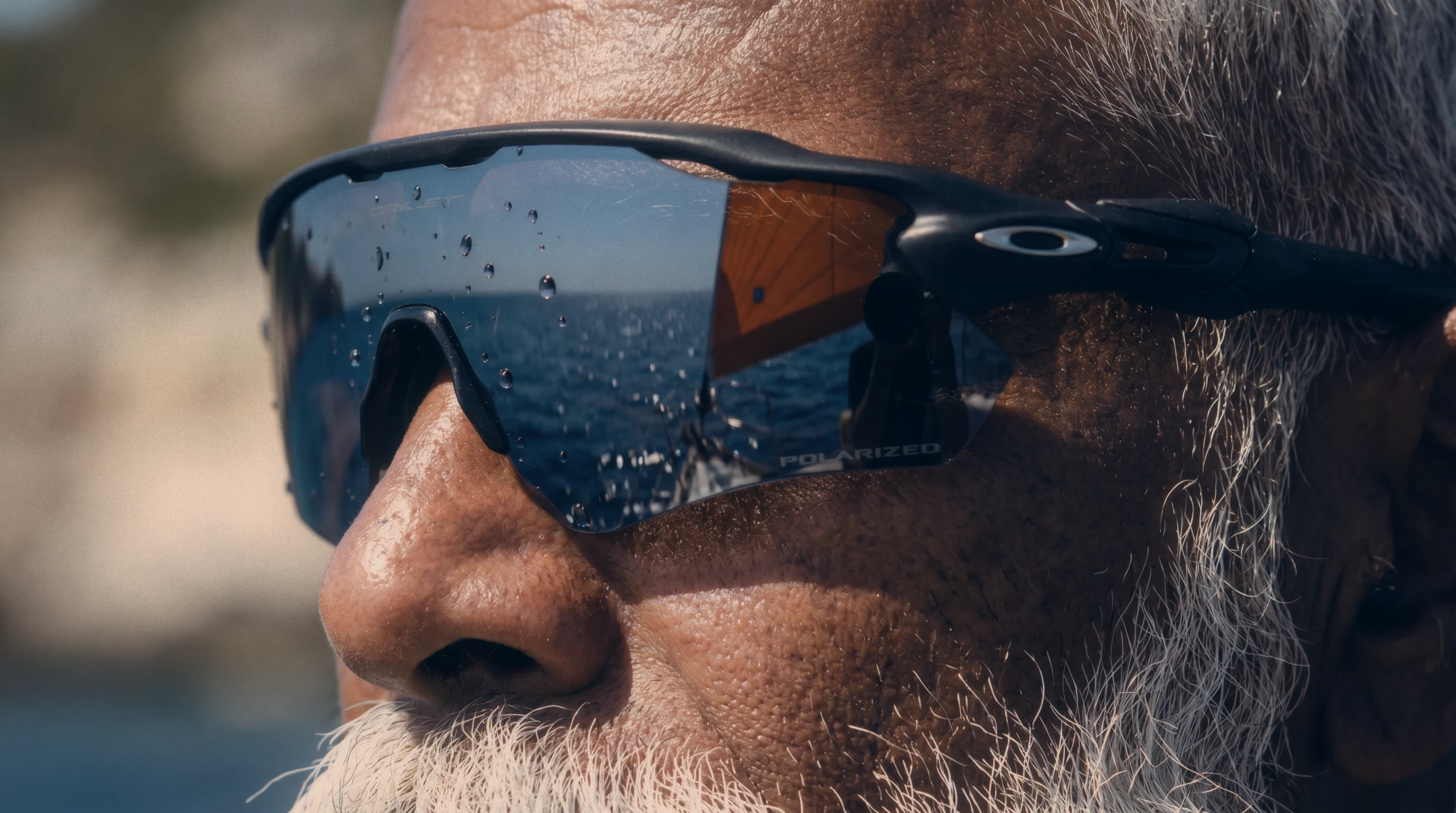 Bearded sailor in Oakley shield sunglasses with the sea reflected