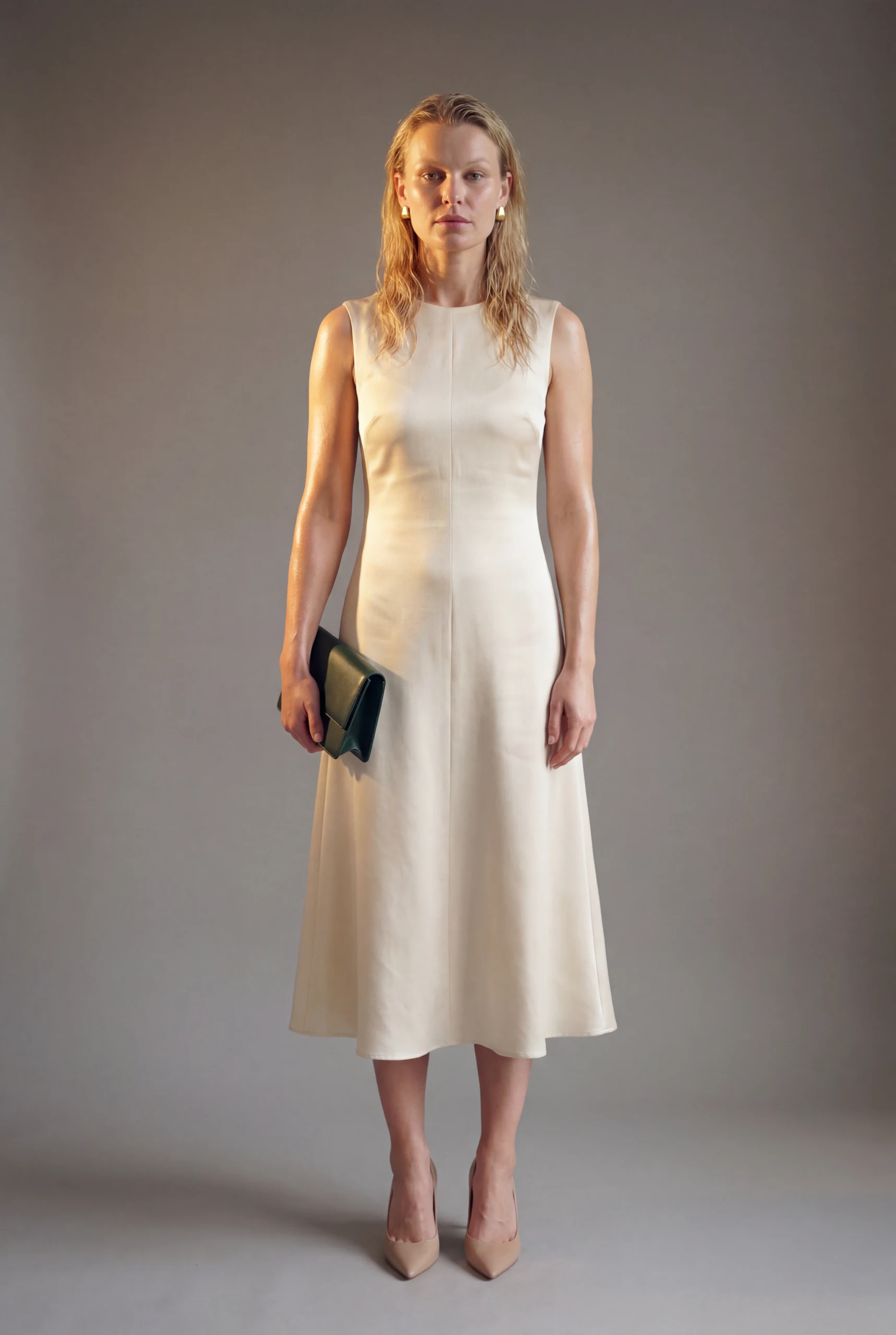 Studio portrait in a cream dress holding a dark clutch